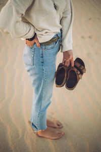 Low section of man standing on sand