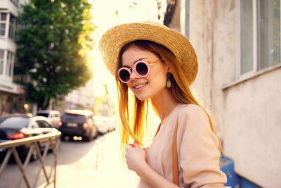 Portrait of smiling young woman wearing sunglasses standing in city