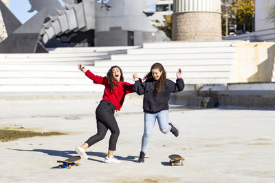 Playful female friends enjoying with skateboard outdoors