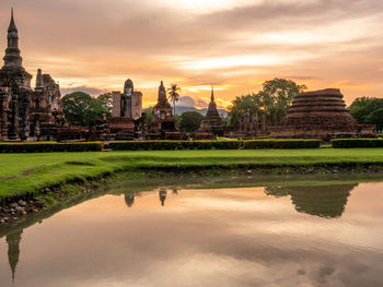 Reflection of temple in building against sky during sunset