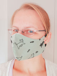 Portrait of woman wearing flu mask standing by wall