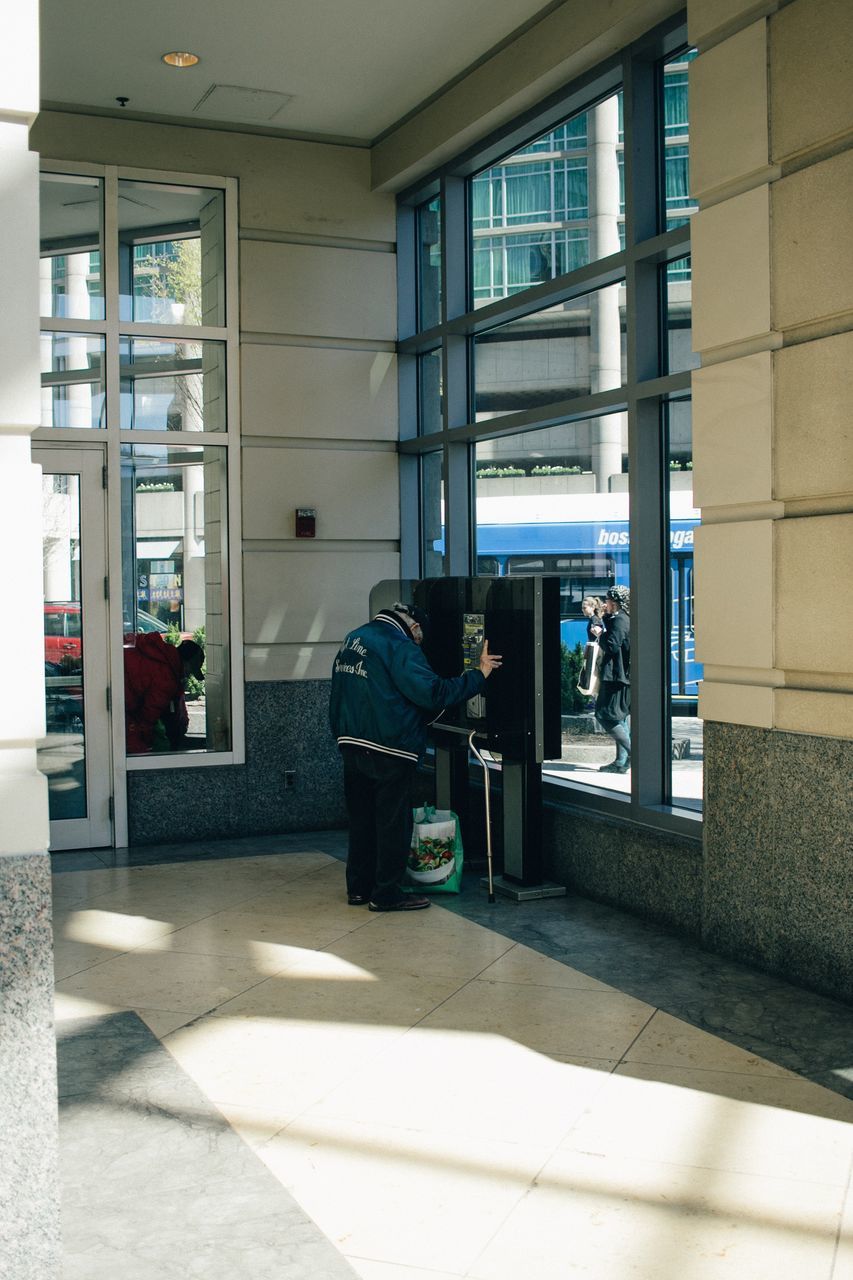 technology, real people, one person, men, day, built structure, full length, lifestyles, architecture, wireless technology, indoors, pay phone, young adult, people