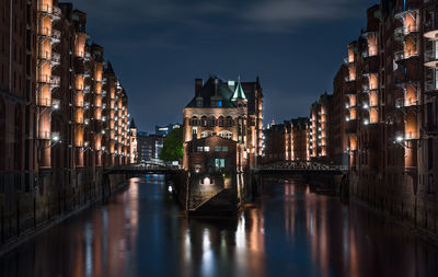 Canal passing through city buildings at night