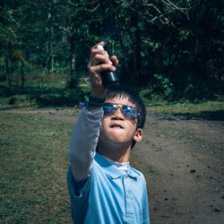 Boy holding perfume sprayer while standing on field