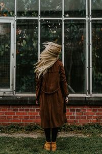 Rear view of woman standing by building