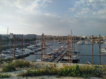 Sailboats moored on river by buildings against sky