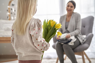 Daughter giving flowers to mother at home