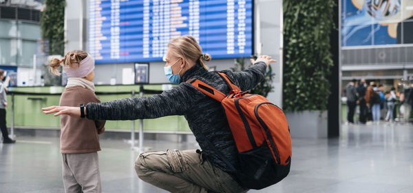 Man and girl watching timetable information at the airport, passengers waiting for a plane. family