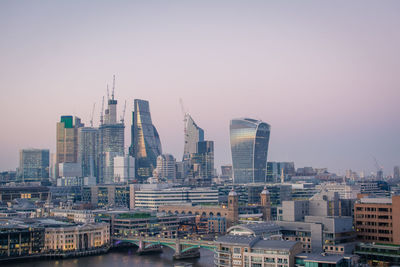 Modern buildings in city against clear sky during sunset