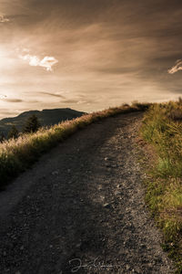 Road amidst field against sky