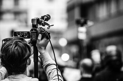 Rear view of man photographing with camera in city