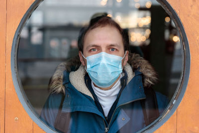 Portrait of man wearing mask seen through window