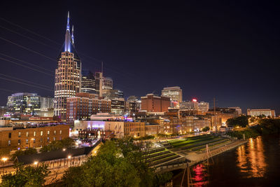 Illuminated buildings in city against sky at night