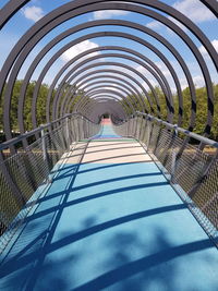 Shadow of person on footbridge against sky