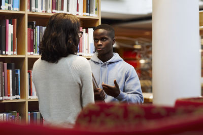 Two students talking in library