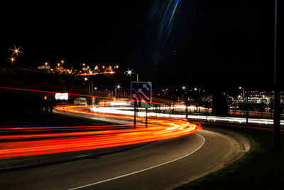 Light trails on road against sky at night