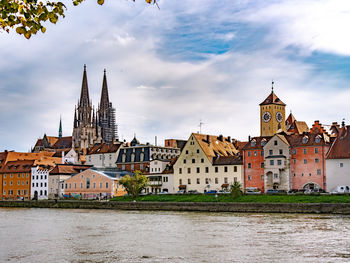 Buildings by river against sky