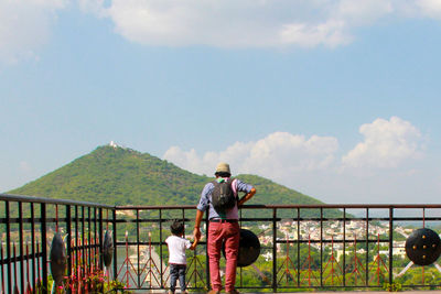 Rear view of woman standing on mountain against cloudy sky
