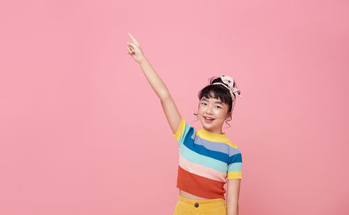 Full length of smiling girl standing against pink background