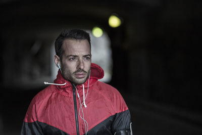 Sporty thoughtful man in jacket listening to music