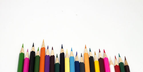 High angle view of colored pencils against white background