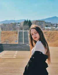 Portrait of beautiful woman standing against sky