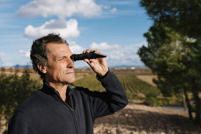 Winemaker looking through refractometer at vineyard