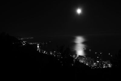 Illuminated sea against sky at night