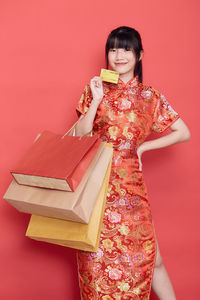 Portrait of smiling woman standing against red background