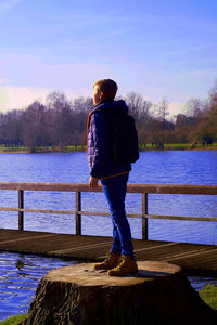 Rear view of man standing by lake against sky