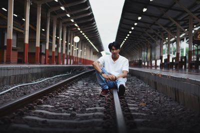 Full length of man sitting on railroad track