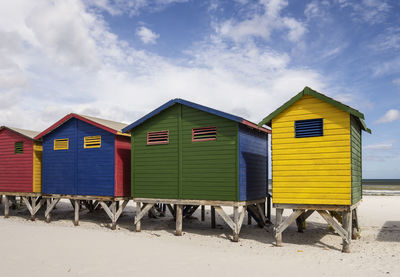 Huts on beach by buildings against sky