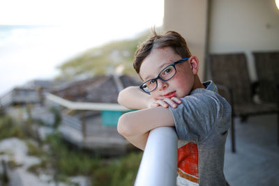 Side view portrait of boy leaning on railing at balcony