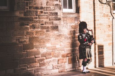 Full length of woman standing against brick wall