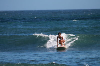 Full length of shirtless man in sea against sky