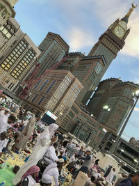 People on street amidst buildings in city against sky