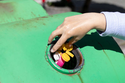 Female hand throwing plastic bottle caps into an urban recycling bin. recycle and reuse concept 