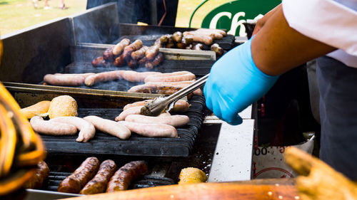 Cropped hand of man making food on barbecue grill
