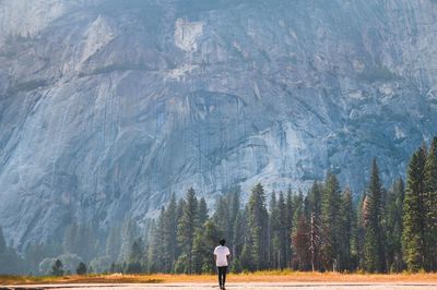 Rear view of man walking on land against rock formation