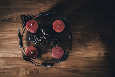 Directly above view of candles and pine cones by christmas decoration on hardwood floor