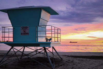 Lifeguard hut on beach against sky during sunset