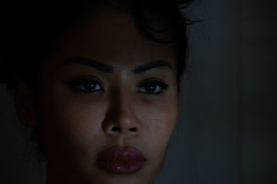 Close-up portrait of young woman in darkroom