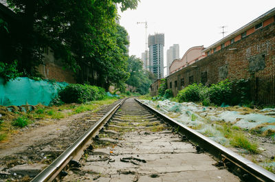 Railroad tracks by buildings in city against sky