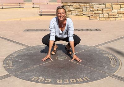 Full length portrait of happy woman crouching at four corners monument