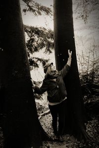 Rear view of man and woman standing by tree trunk