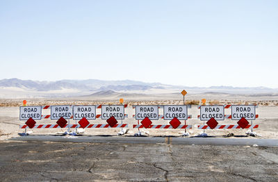 Warning signs on mountain road against clear sky