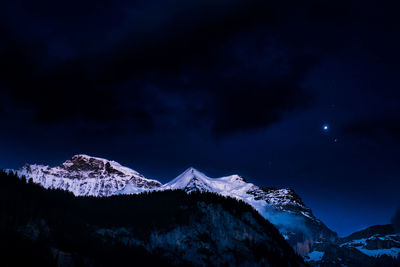 Scenic view of snowcapped mountains against sky at night