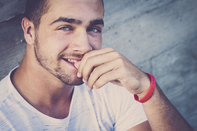 Portrait of smiling young man biting finger