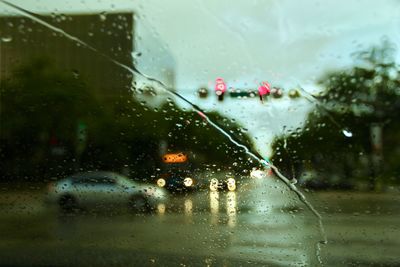 Road in city seen through wet windshield during rain