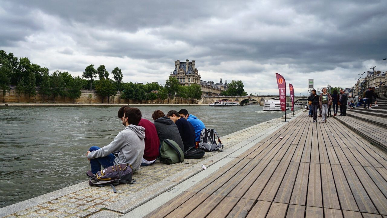 sitting, young adult, sky, togetherness, outdoors, leisure activity, women, young women, men, rear view, water, full length, river, adult, cloud - sky, people, friendship, adults only, tree, community, day